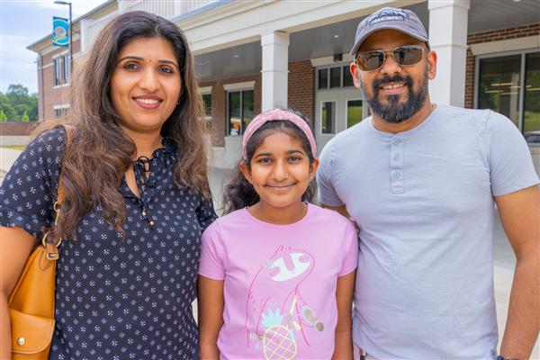 mom, dad and girl smiling in front of CSES